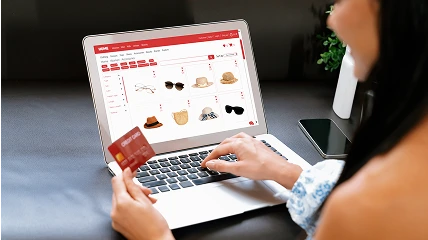 Woman is watching on e-commerce shop on the laptop display and holding the card.