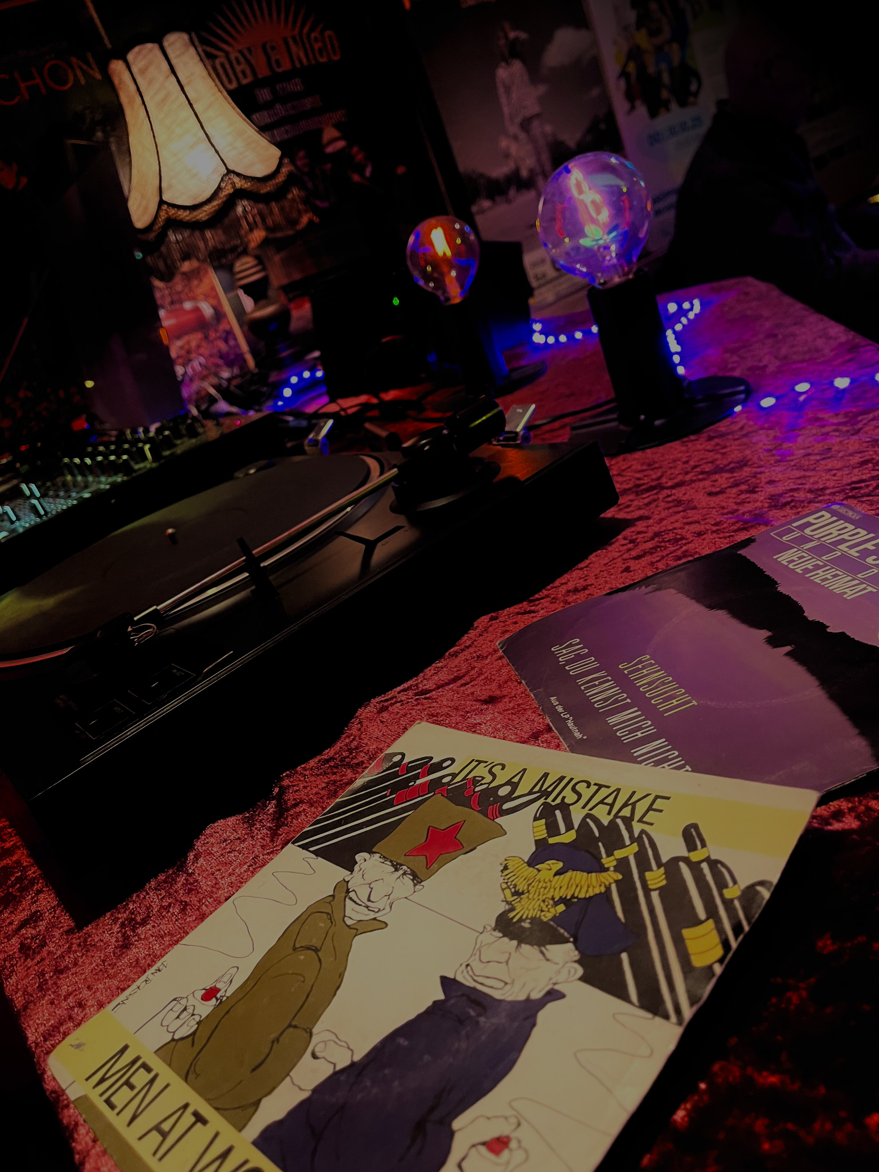 Text "KOMM Auflegen!" und "Open Vinyl Bar" vor einem Hintergrund mit Schallplatten 