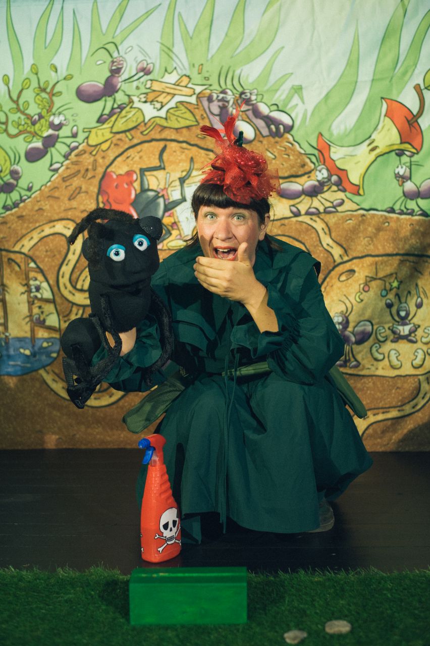 Eine Schauspielerin verkleidet als Ameise knabbert an einem Apfel