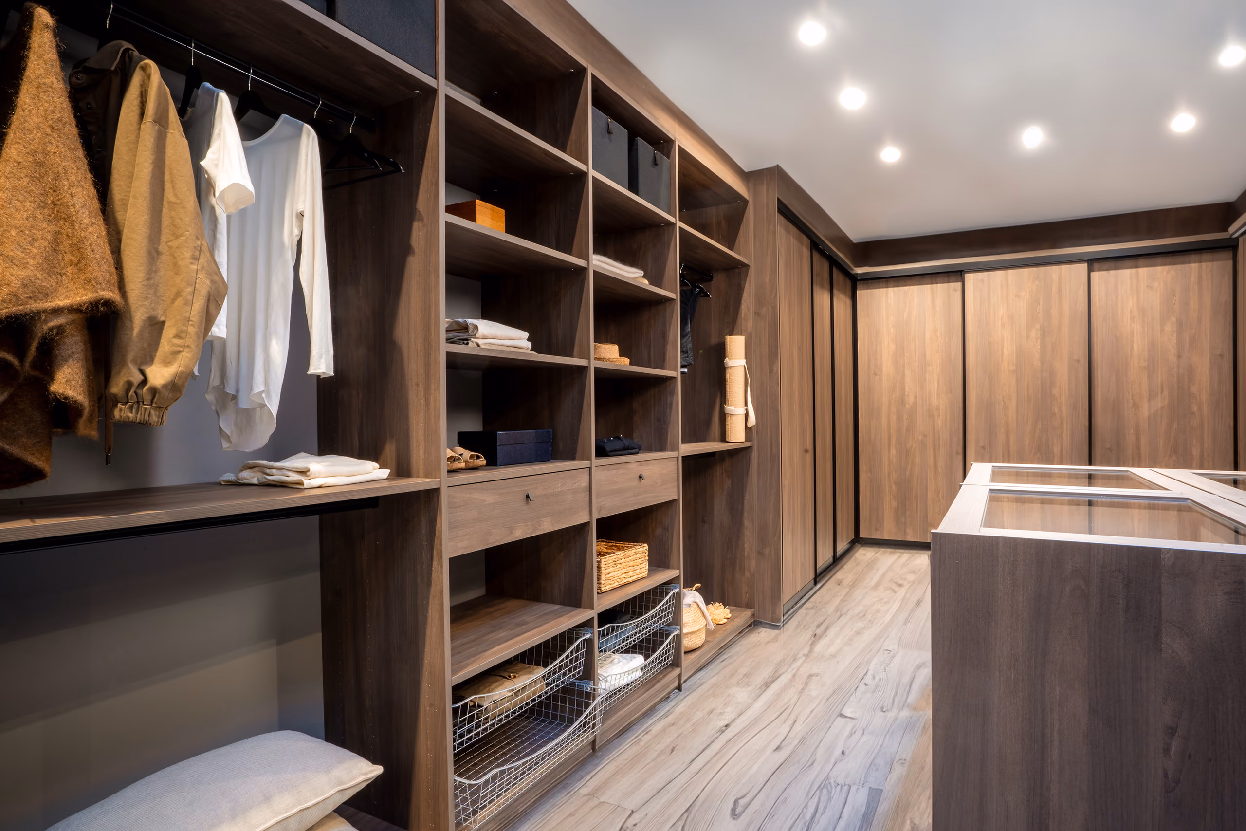 Innebygd garderobe i mørkt tre med åpne hyller, hengestang og skyvedører i en romslig walk-in-closet.