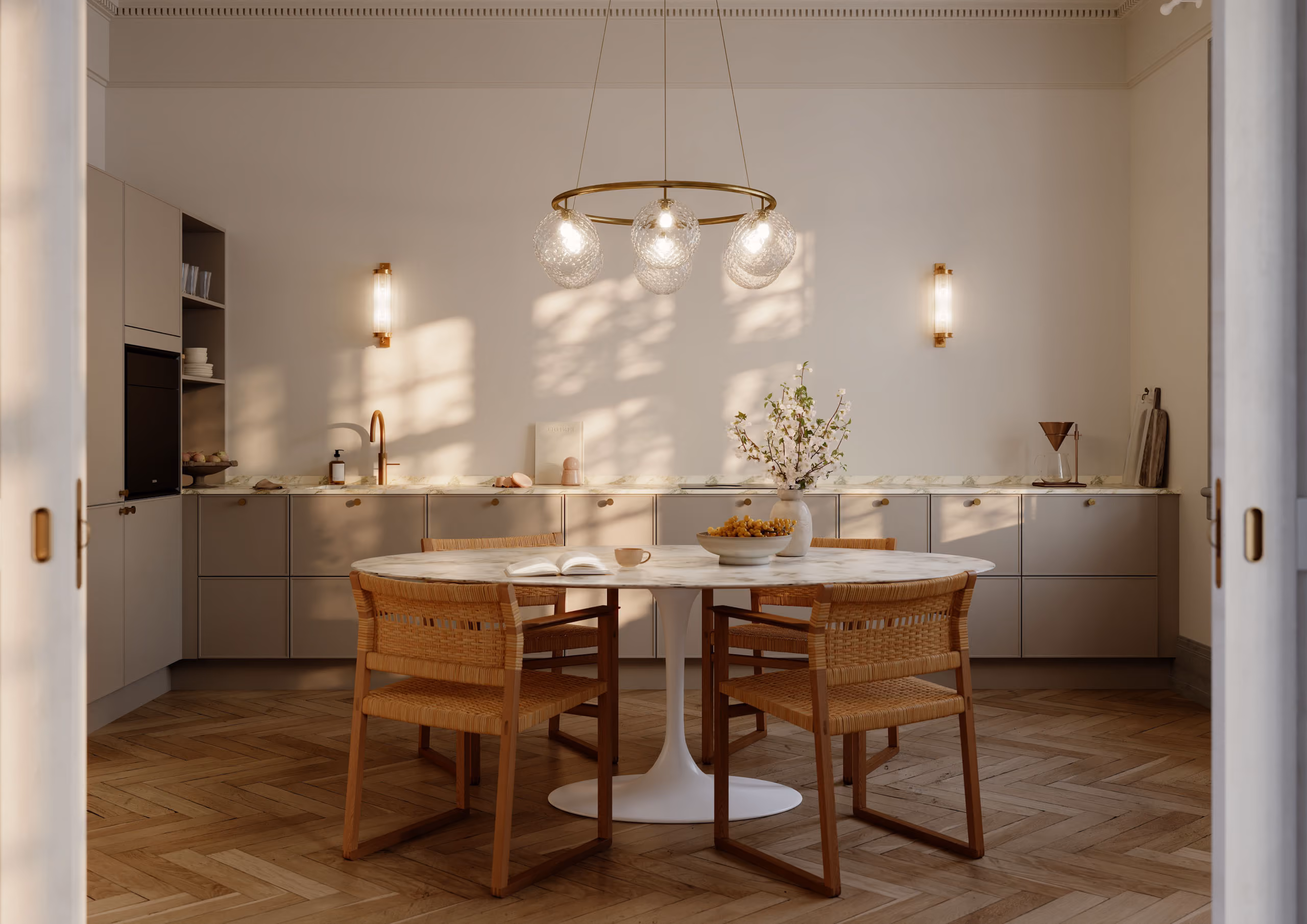 Elegant kjøkken med marmorbord, rotting stoler og messinglampe over spiseplassen, beige kjøkkeninnredning i bakgrunn.