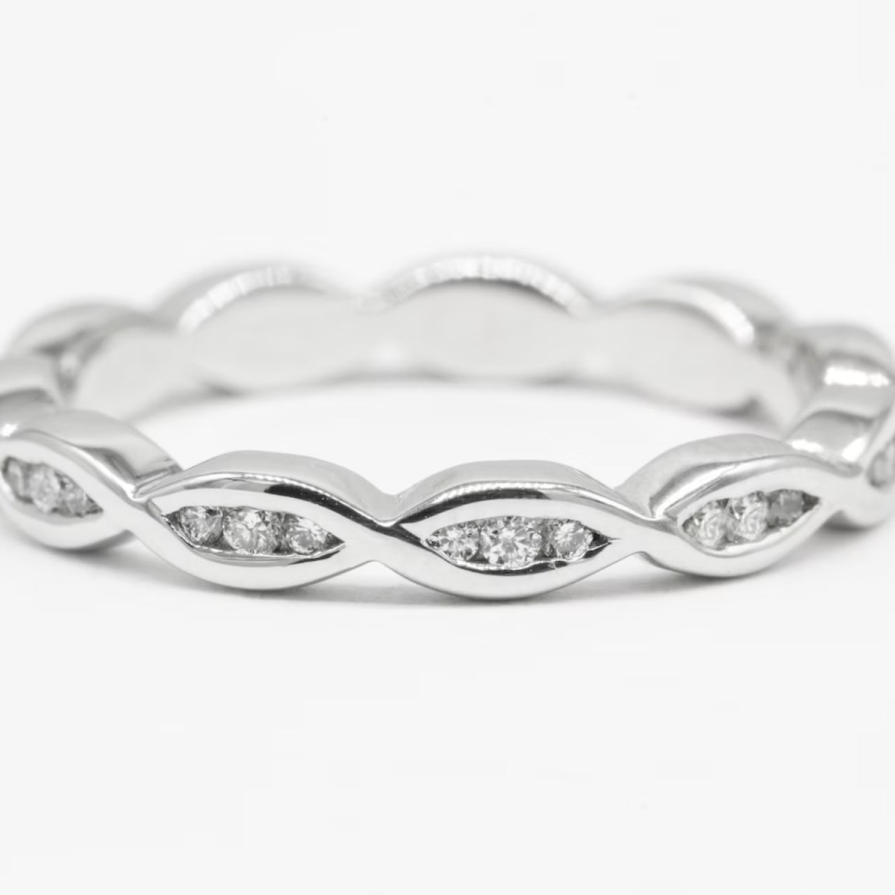 Silver ring with repeating marquise shapes set with small round diamonds.
