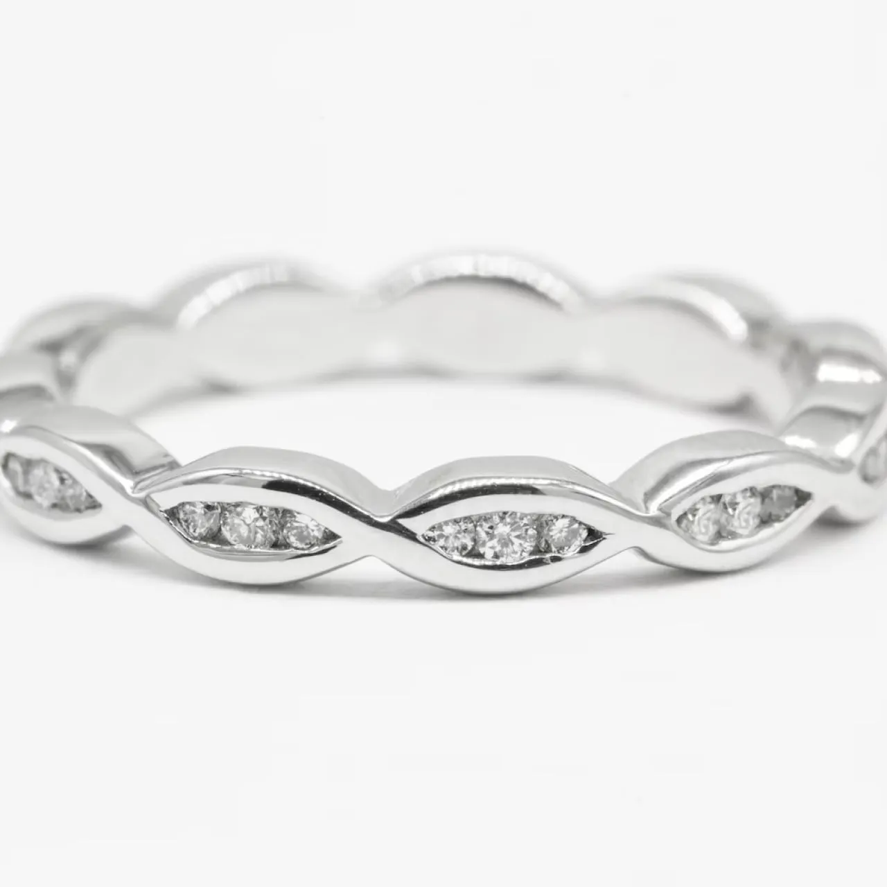 Silver ring with a twisted pattern inset with small round clear gemstones.