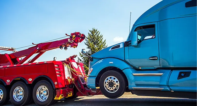 A blue semi truck with a crane on the back of it.
