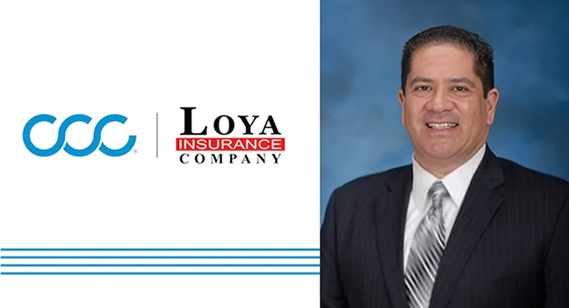 A man in a suit and tie standing in front of a company logo.