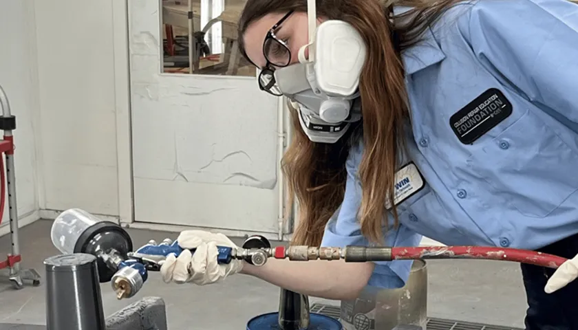 A woman in a gas mask working on a pipe.