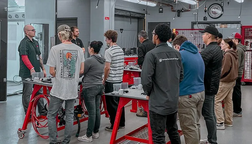 A group of people standing around a red table.