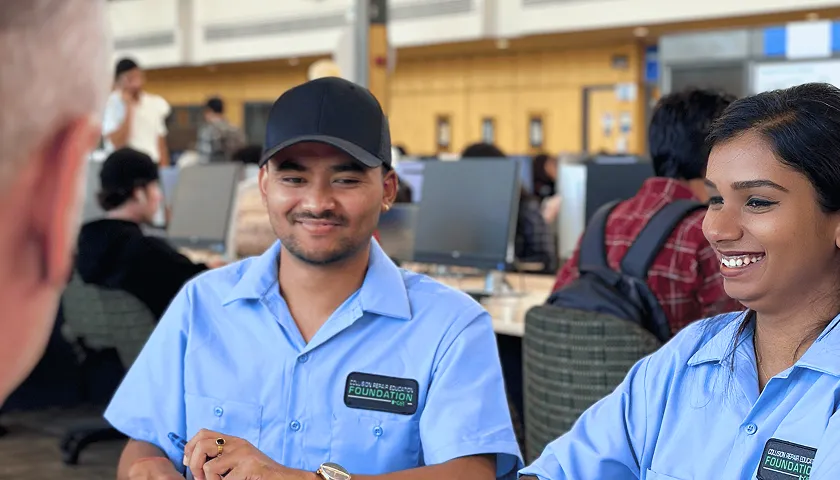 A man and a woman sitting at a table in front of computers.