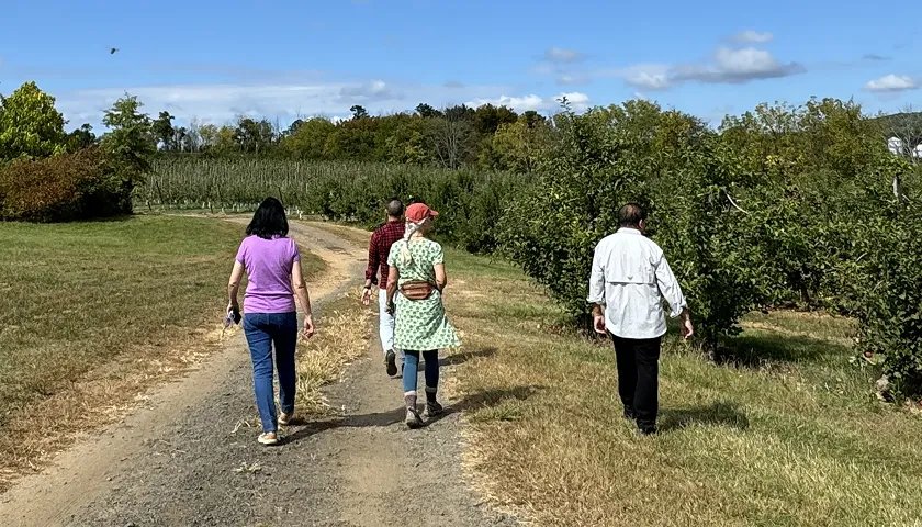 A group of people walking down a dirt road.