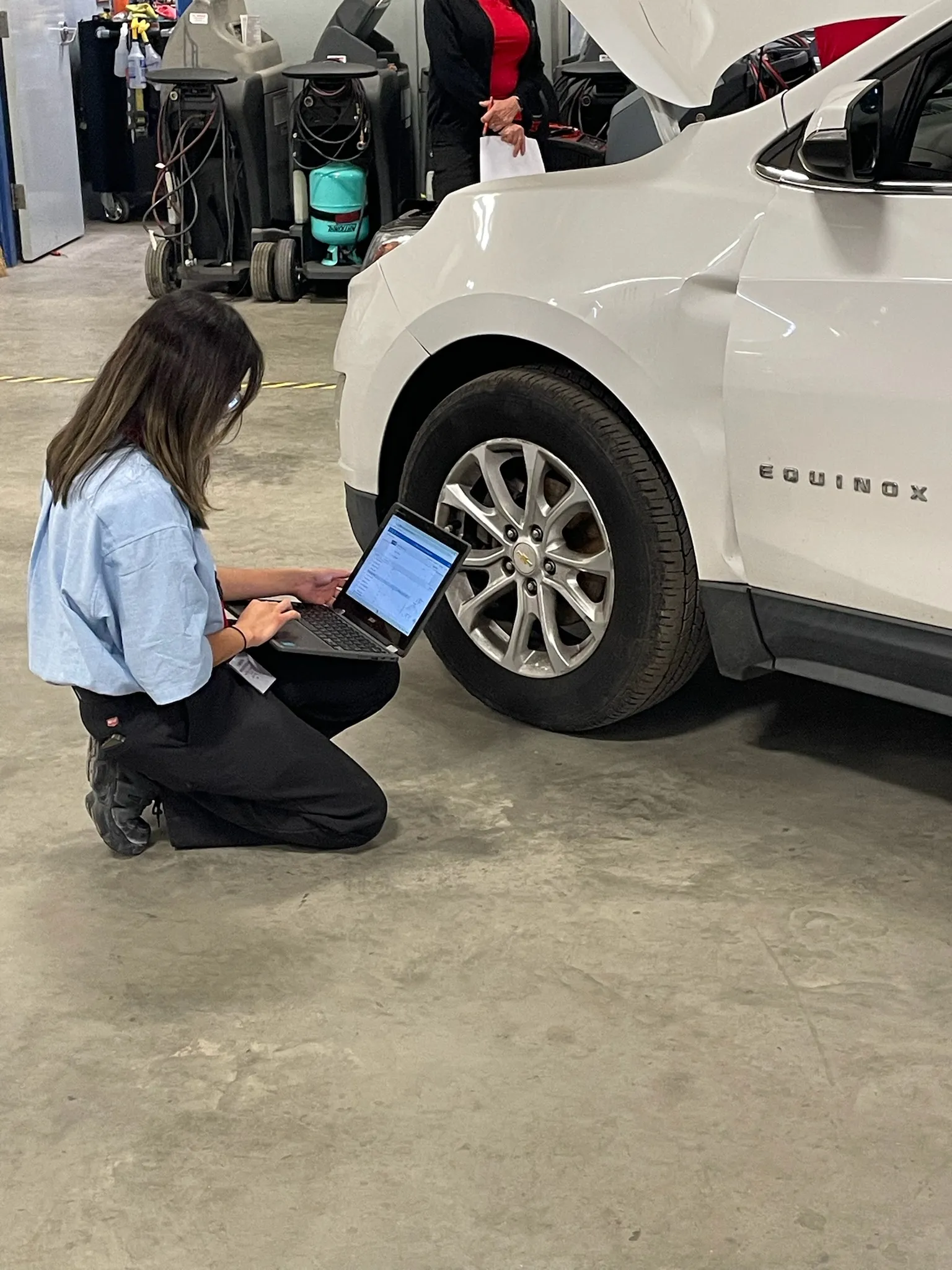 Three men in blue shirts looking at a tablet.
