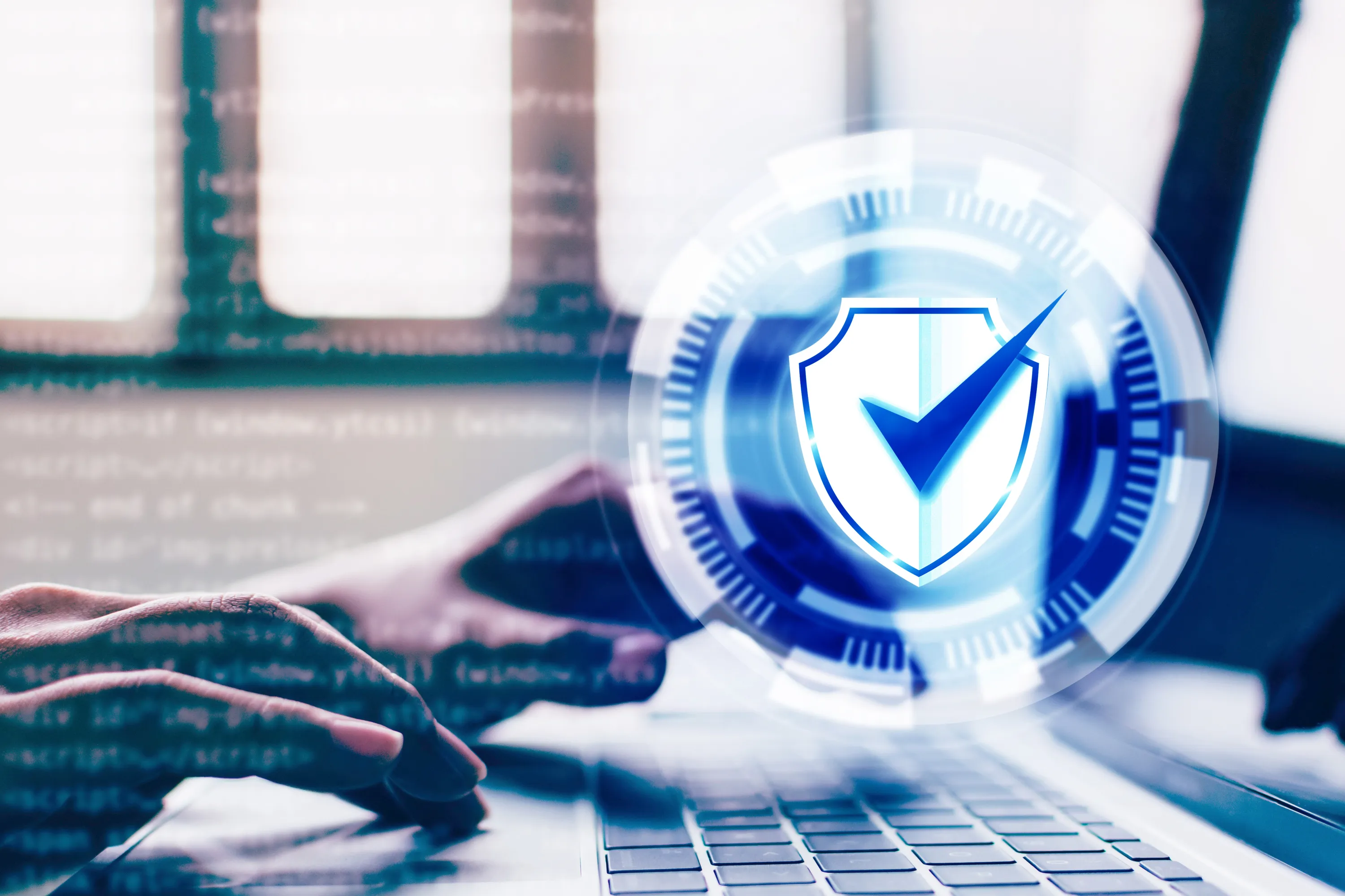Hands typing on a laptop keyboard with a glowing shield and checkmark representing cybersecurity.