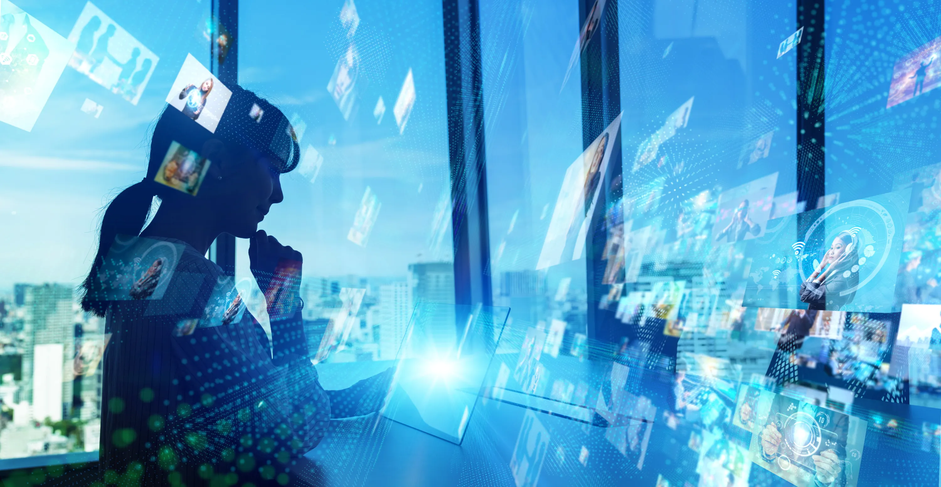 Silhouette of a woman using a tablet with floating digital images and cityscape background.