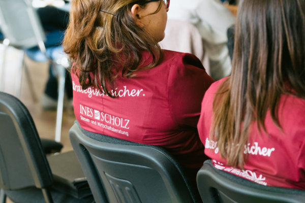 Zwei Frauen mit braunen Haaren tragen rote T-Shirts mit der Aufschrift INES SCHOLZ.