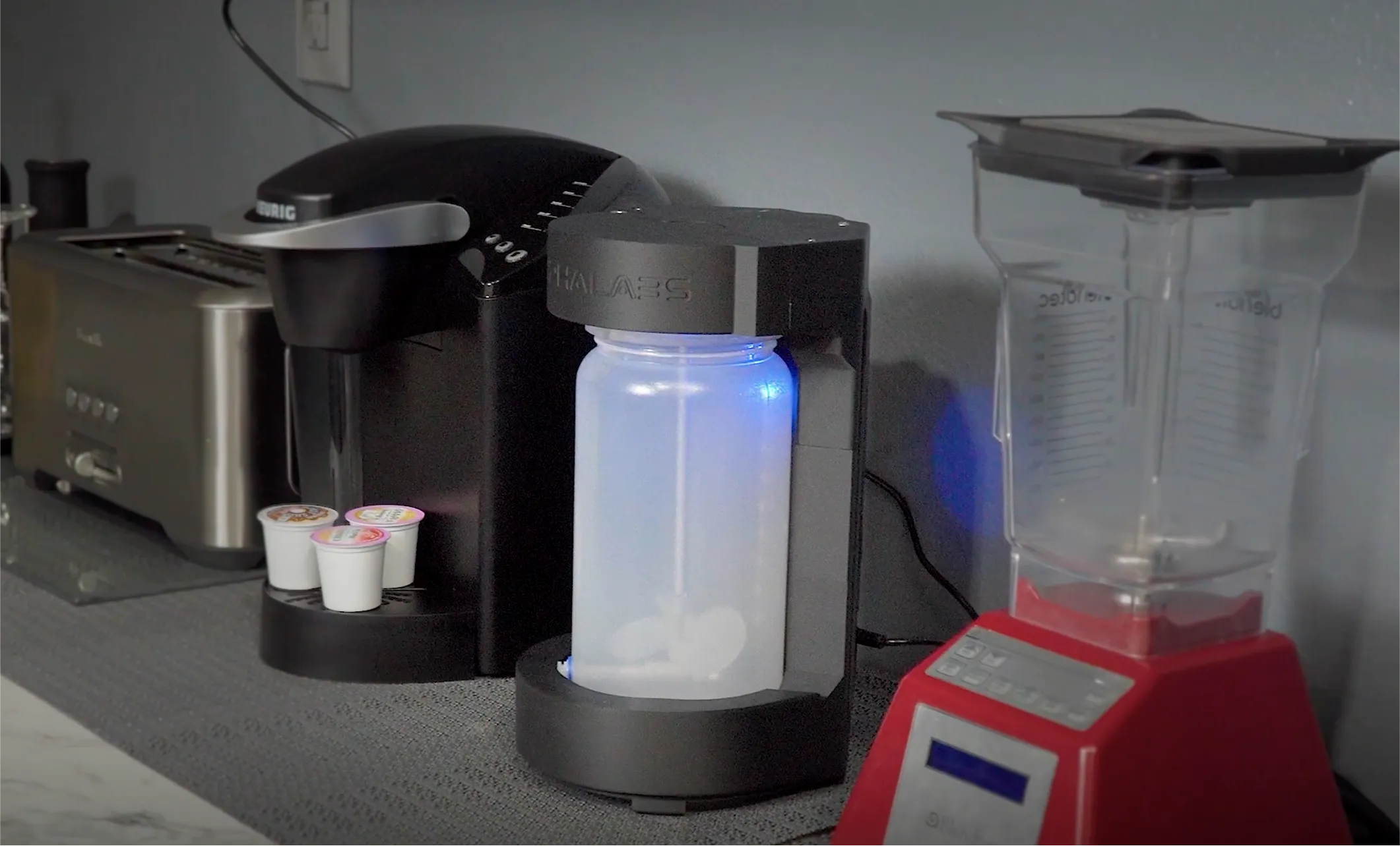 A black coffee maker with a blue light on the side.
