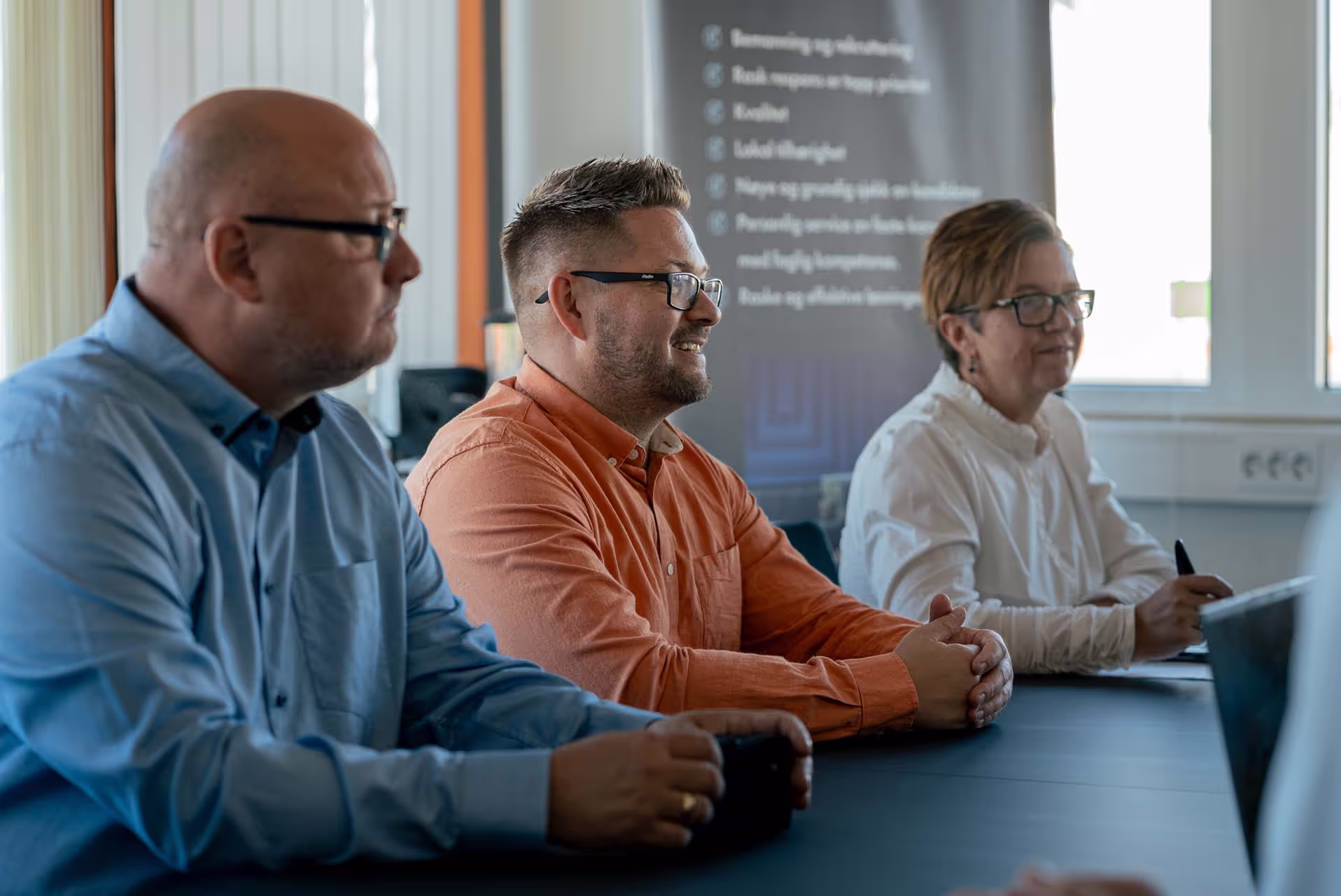 Tre ansatte fra Vikarkompaniet sitter ved et bord og jobber