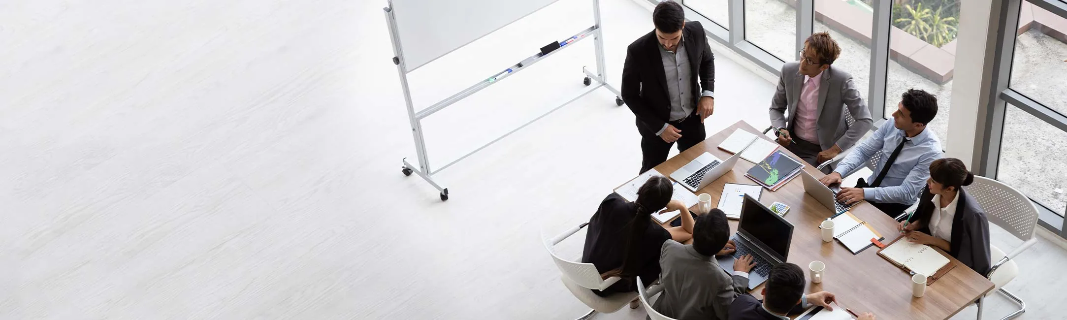 A diverse team of professionals engaged in a meeting around a table, with a presentation board in the background.