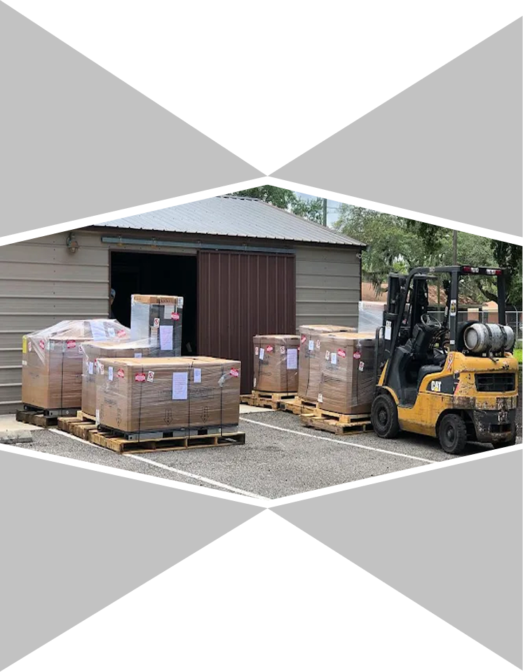 A forklift is moving pallets of equipment outside of a warehouse.