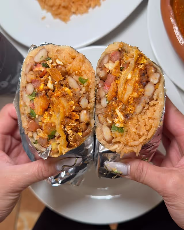A person showing burrito cut in half