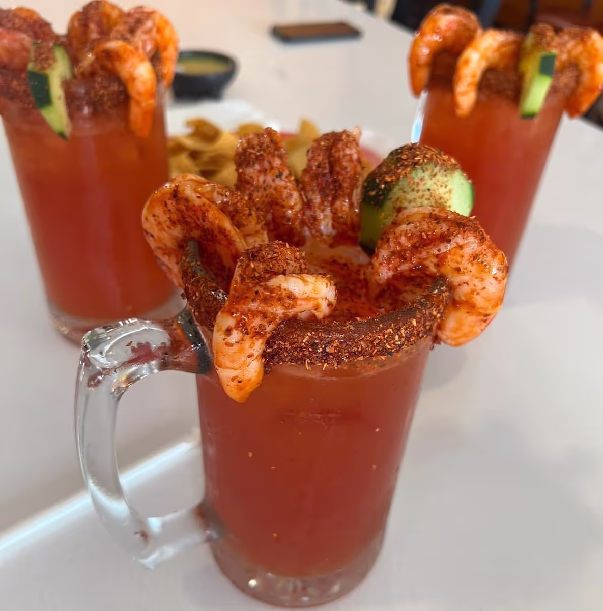 A beer with some shrimps and chili powder on the top