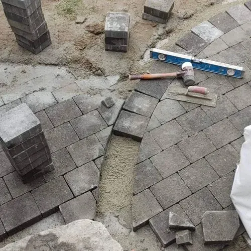Curved stone paver patio under construction with tools on site