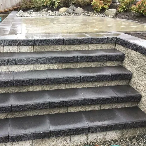 Newly built black and gray concrete steps leading to a wet stone patio