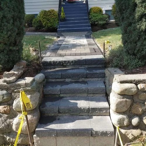 Stone steps and walkway installation with retaining walls leading to front porch