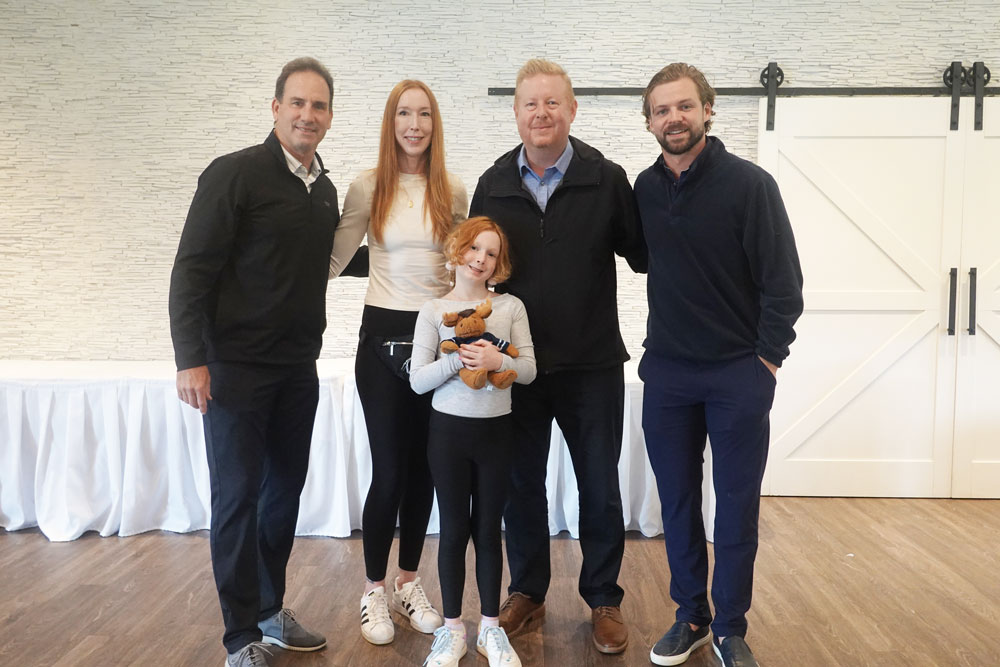 Dream kid Elliot holding a stuffed moose with her family meeting Josh Morrissey and Coach Scott Arniel.