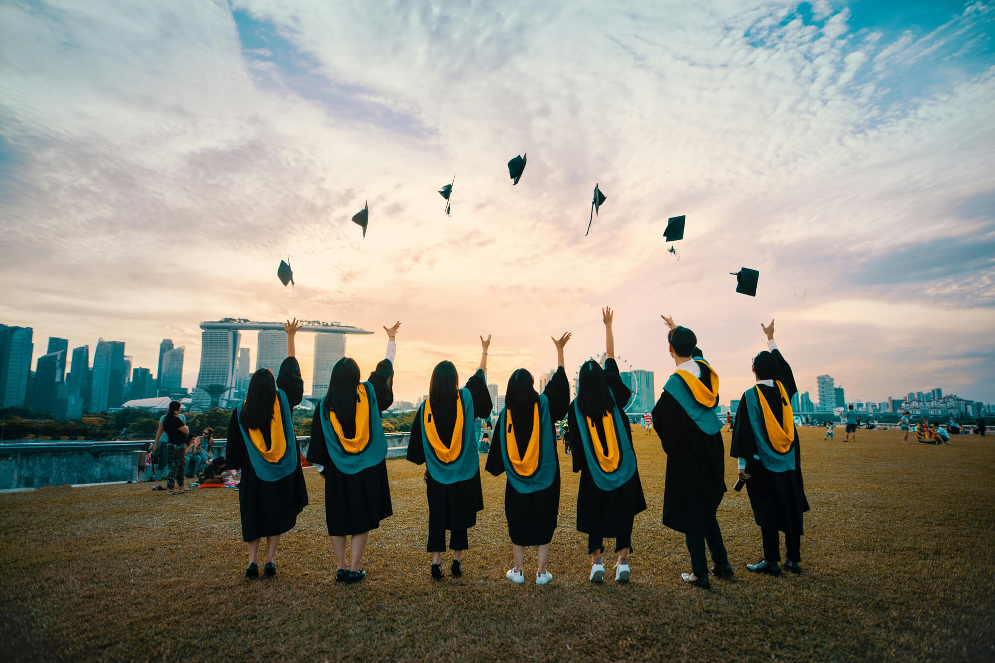 Graduating students throwing their caps in a field. 