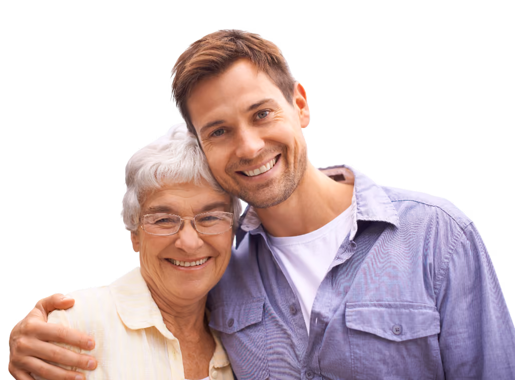Smiling adult man with his arm around an older woman, both looking at the camera outdoors. The woman is wearing glasses and a light shirt, while the man is wearing a casual blue button-up shirt.
