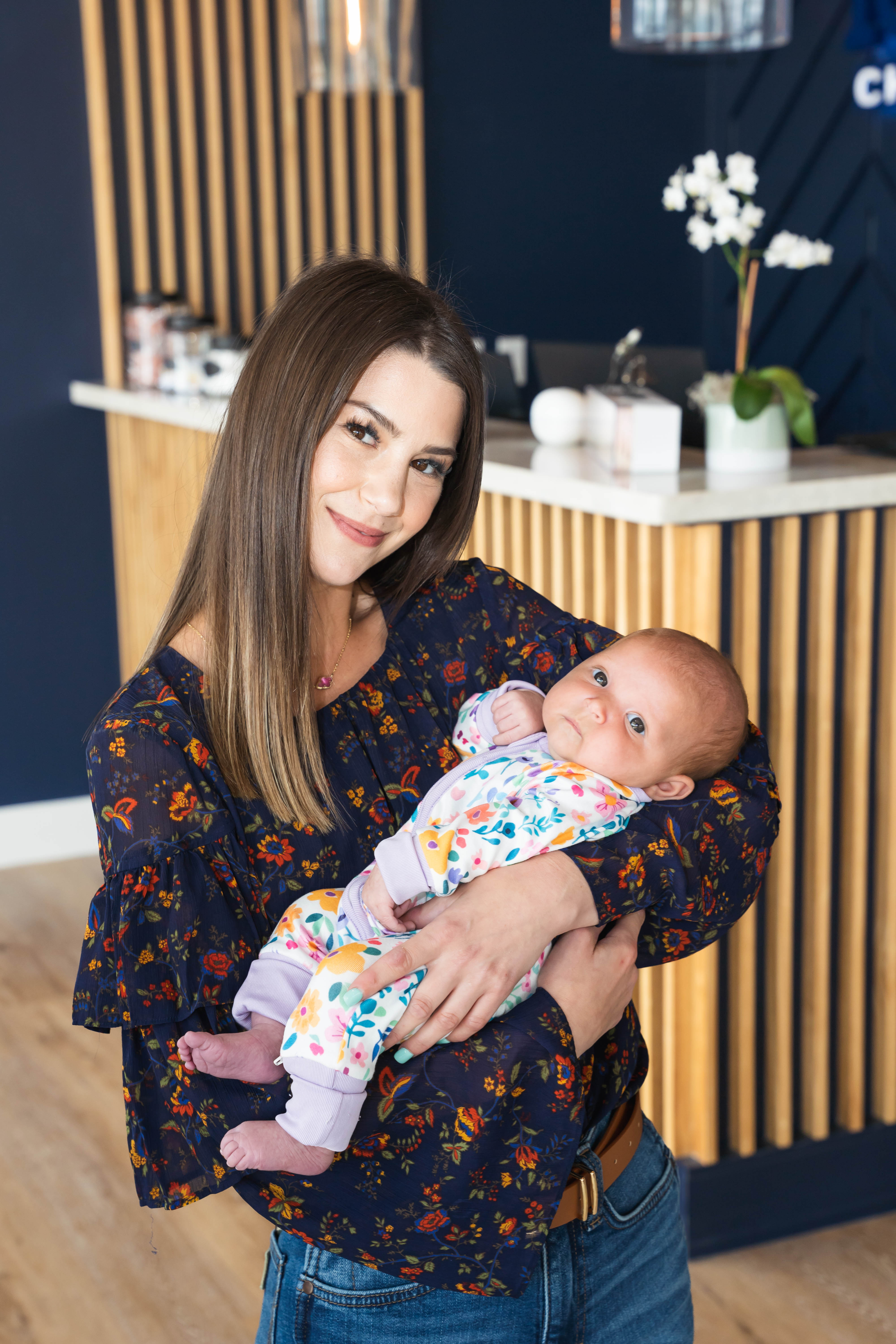 Young mother receiving infant chiropractic adjustment in bright room, promoting holistic health and baby care benefits.