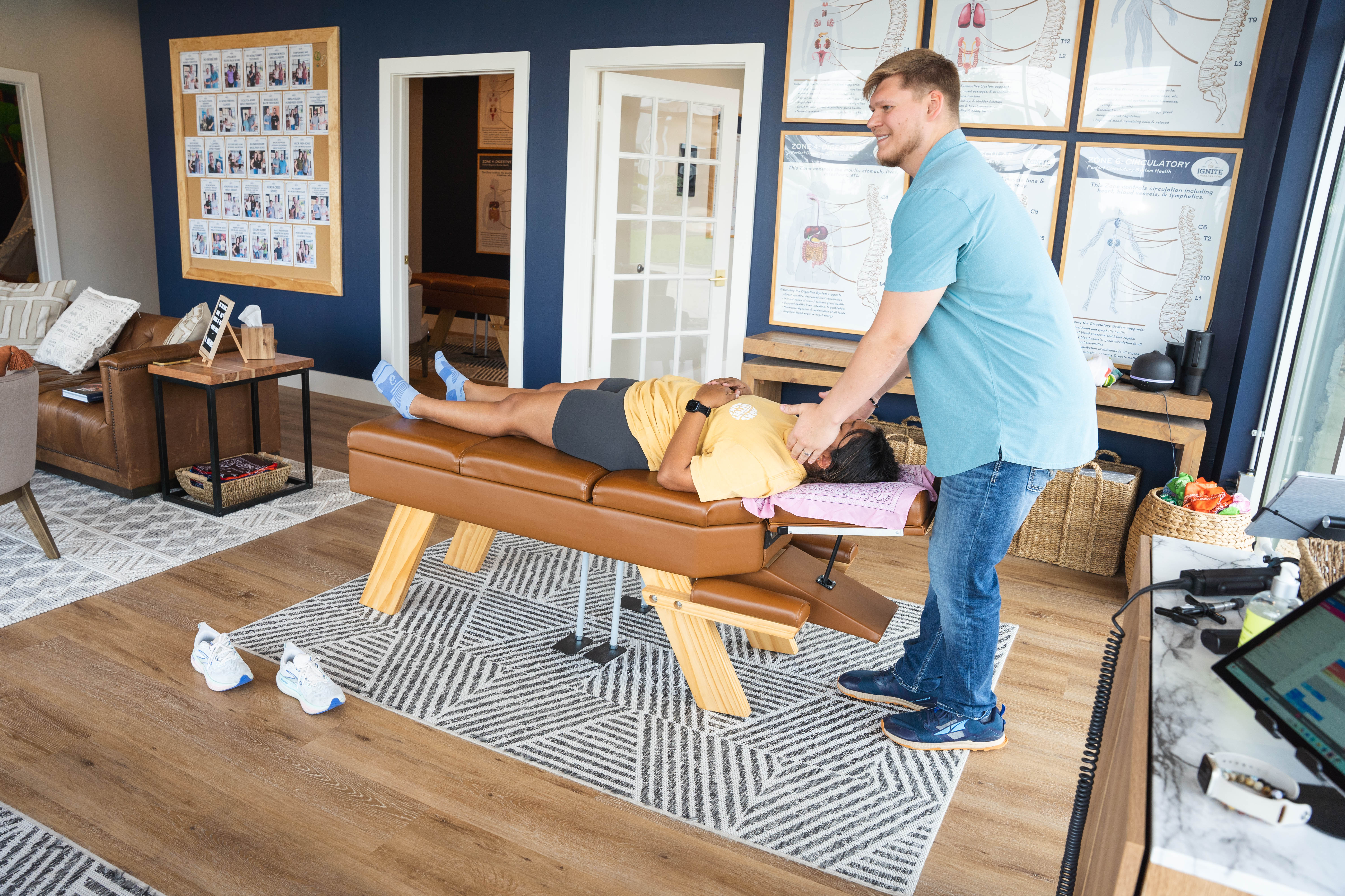 Chiropractor performing spinal adjustment in modern clinic with anatomical posters, highlighting nervous system and wellne...