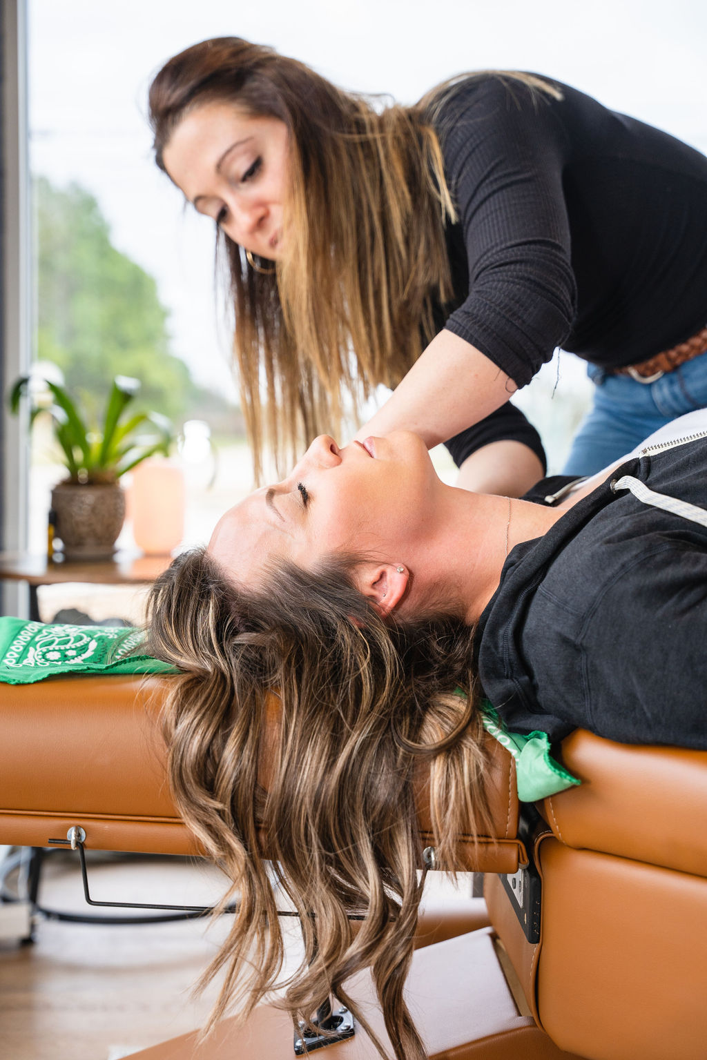 Chiropractor adjusting infant on cushioned table in bright room, highlighting holistic health and parenting care.