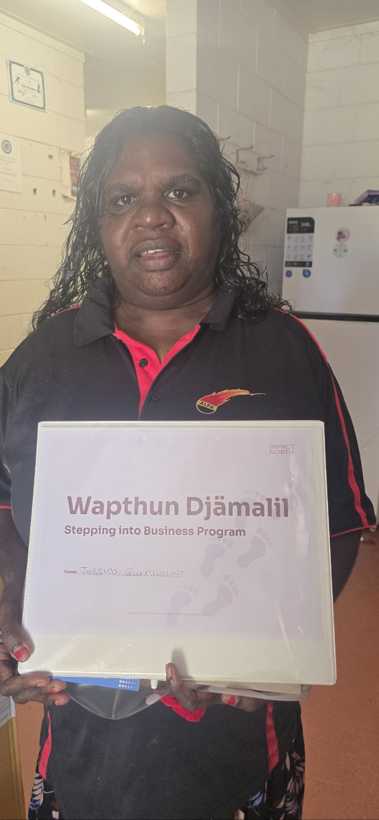 Jessica Gurruwiwi holding stepping into business work book.