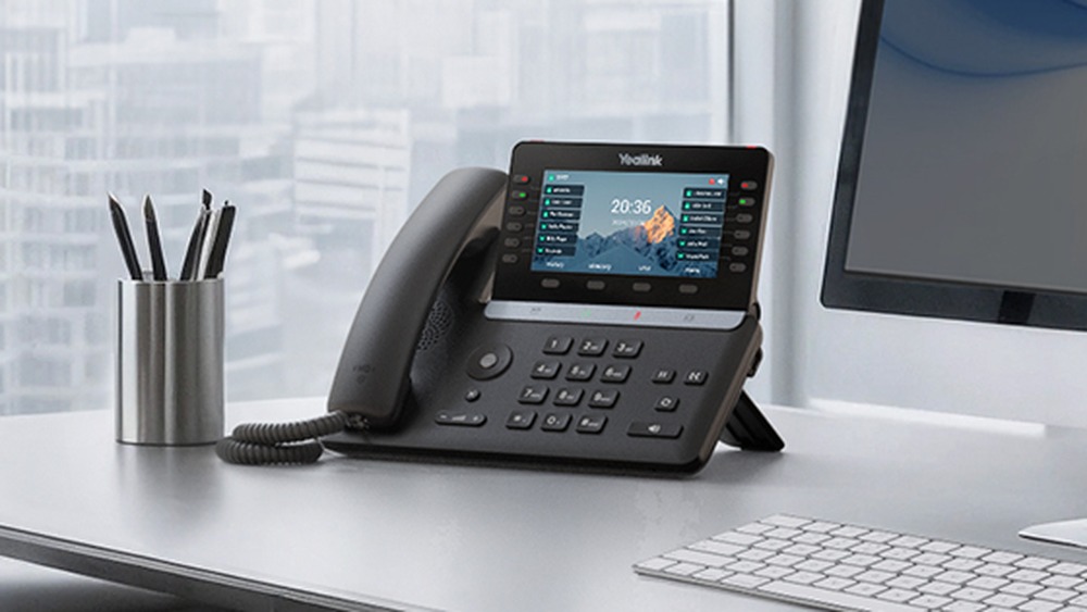 A Yealink T85W desk phone on a front-desk workstation