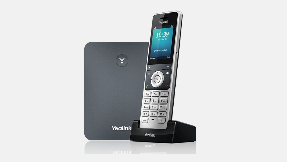 A Yealink W76P cordless DECT handset in its charger beside the W70B base