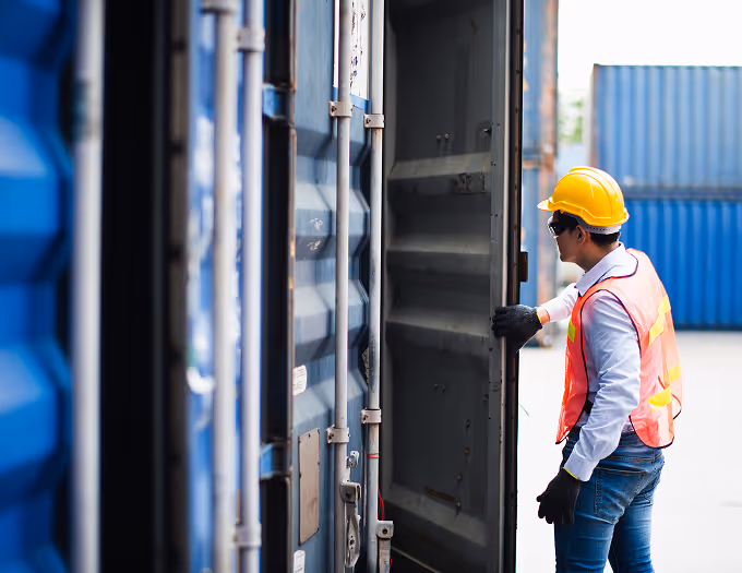 A man in a yellow vest is opening a container.