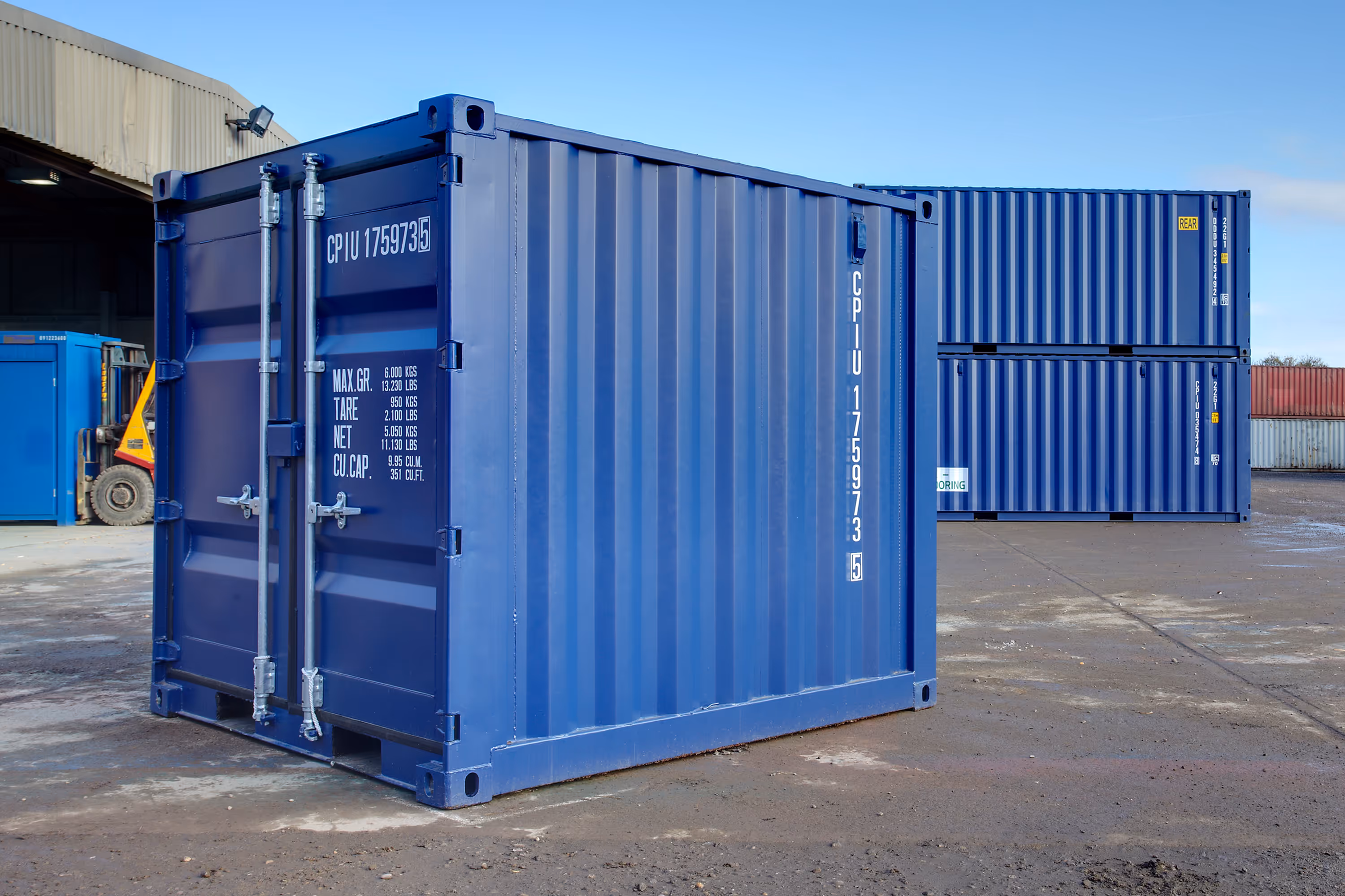 A large blue shipping container is sitting on a concrete surface.