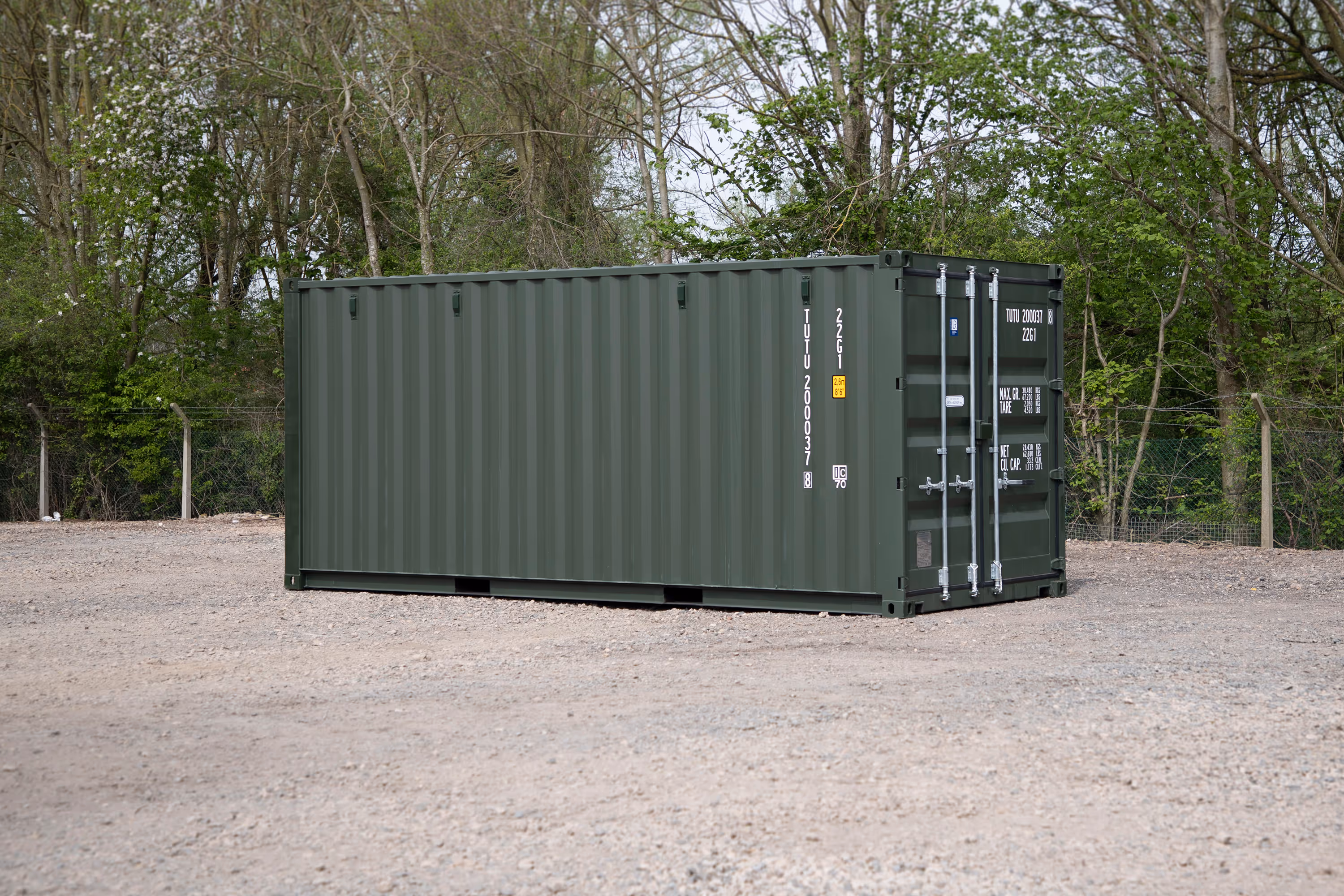 A large green shipping container is parked in a lot.