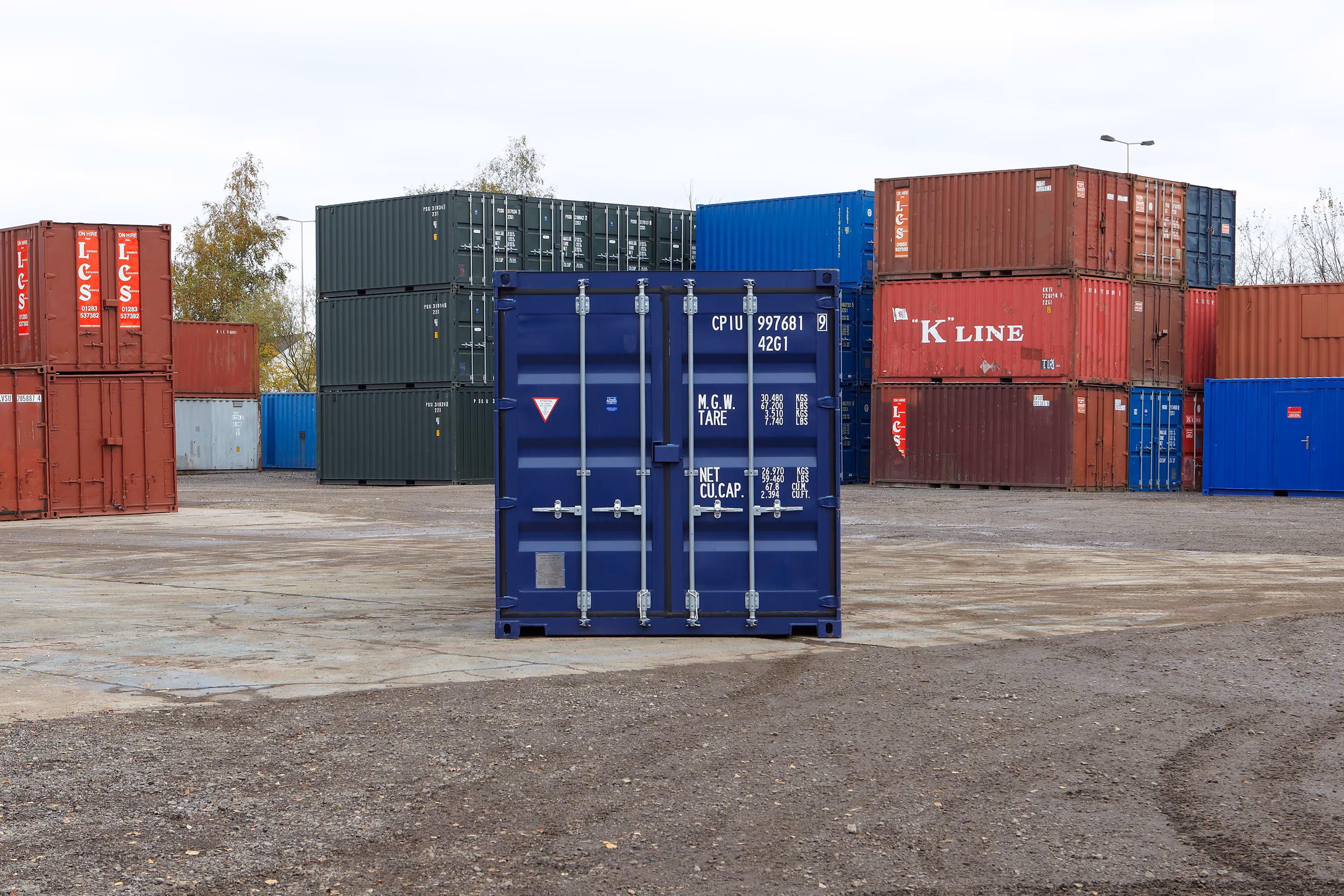 A blue shipping container is sitting in a parking lot.