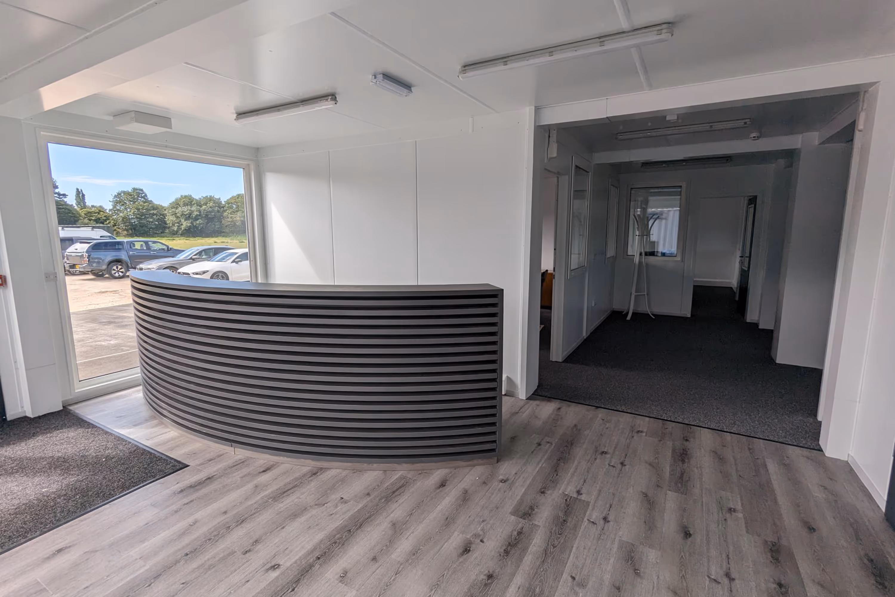 A large wooden desk in a room with a white wall.