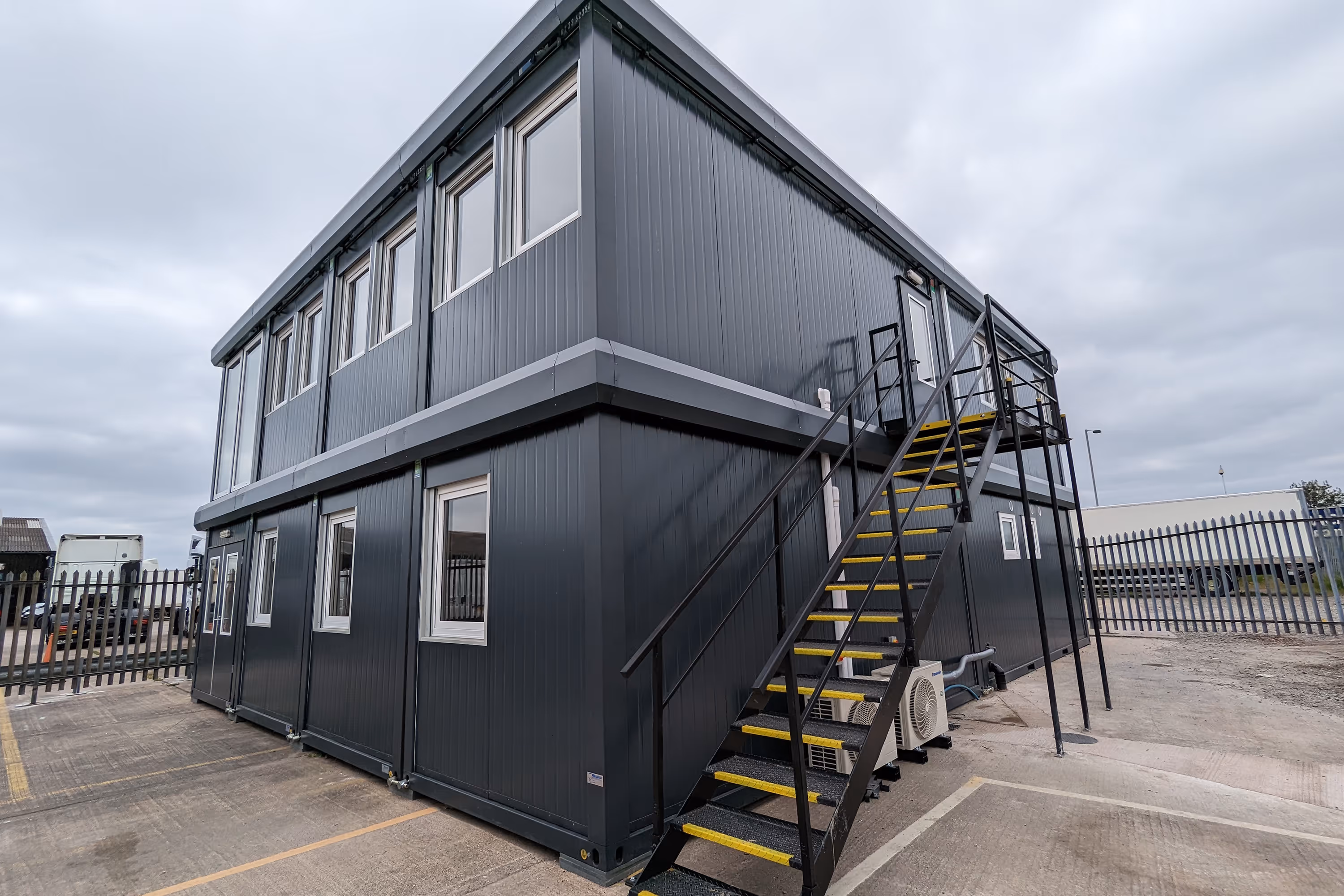 A large black modular building with a metal staircase.