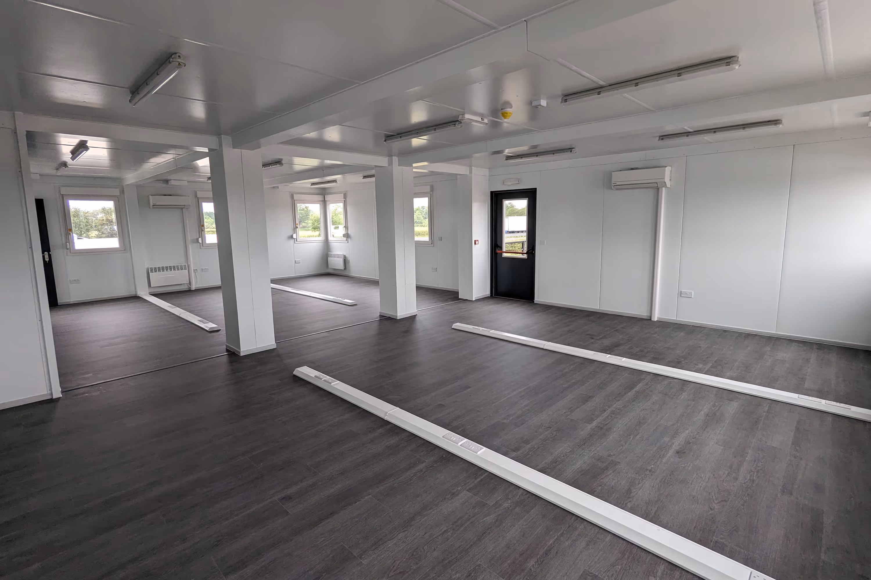 A large white modular building with a black door and a white door.