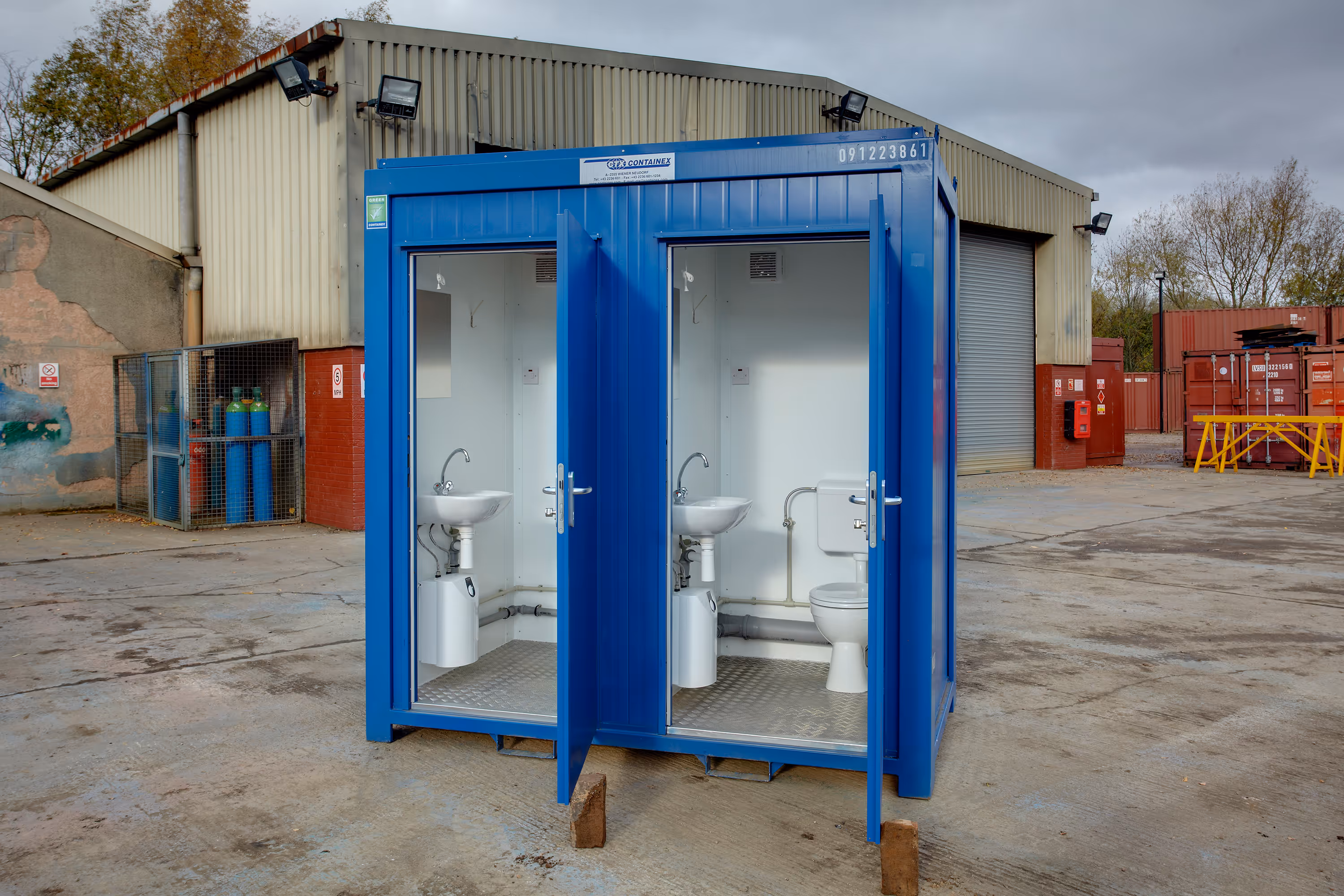 A blue portable bathroom with two toilets.