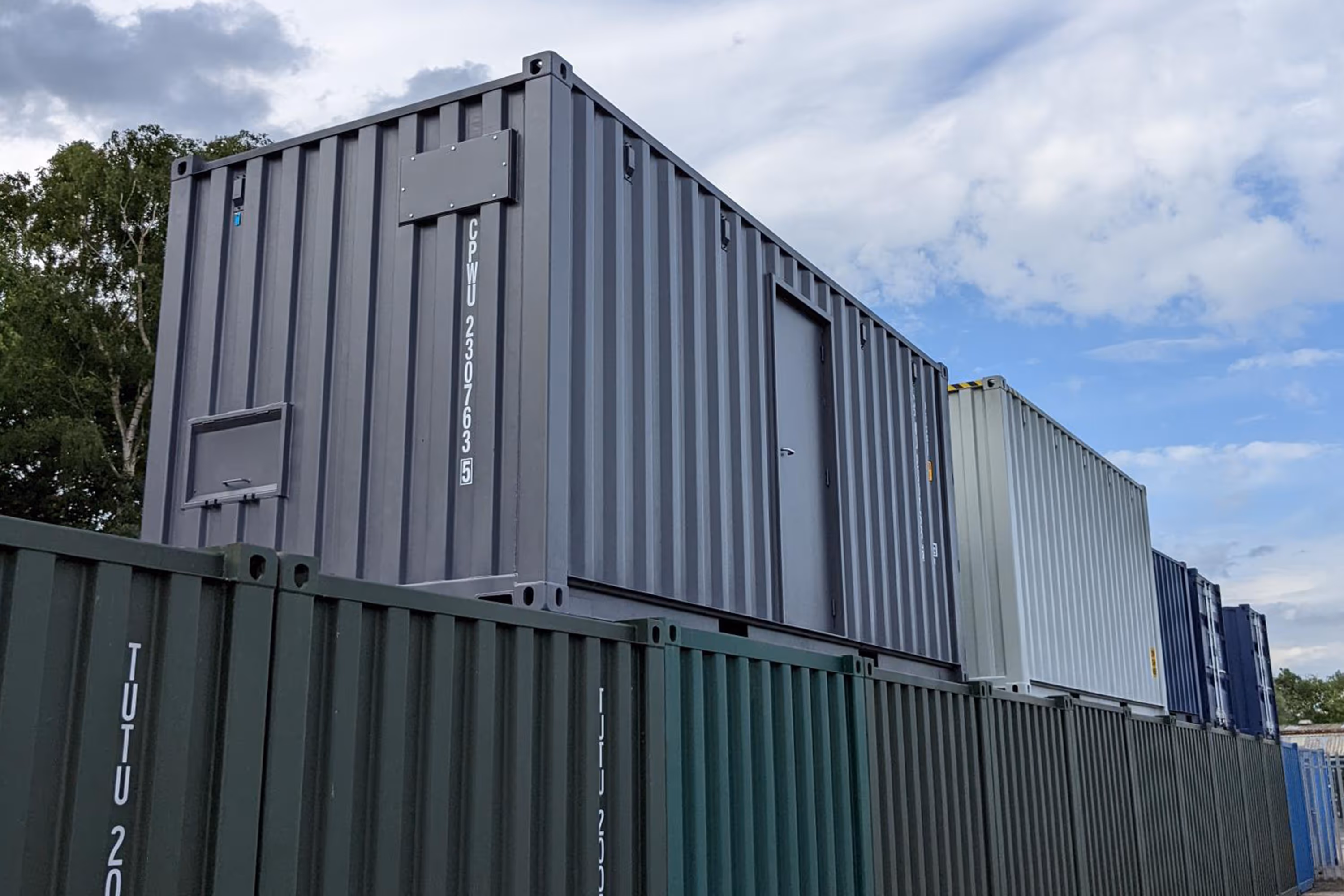 A large grey shipping container with a white door.