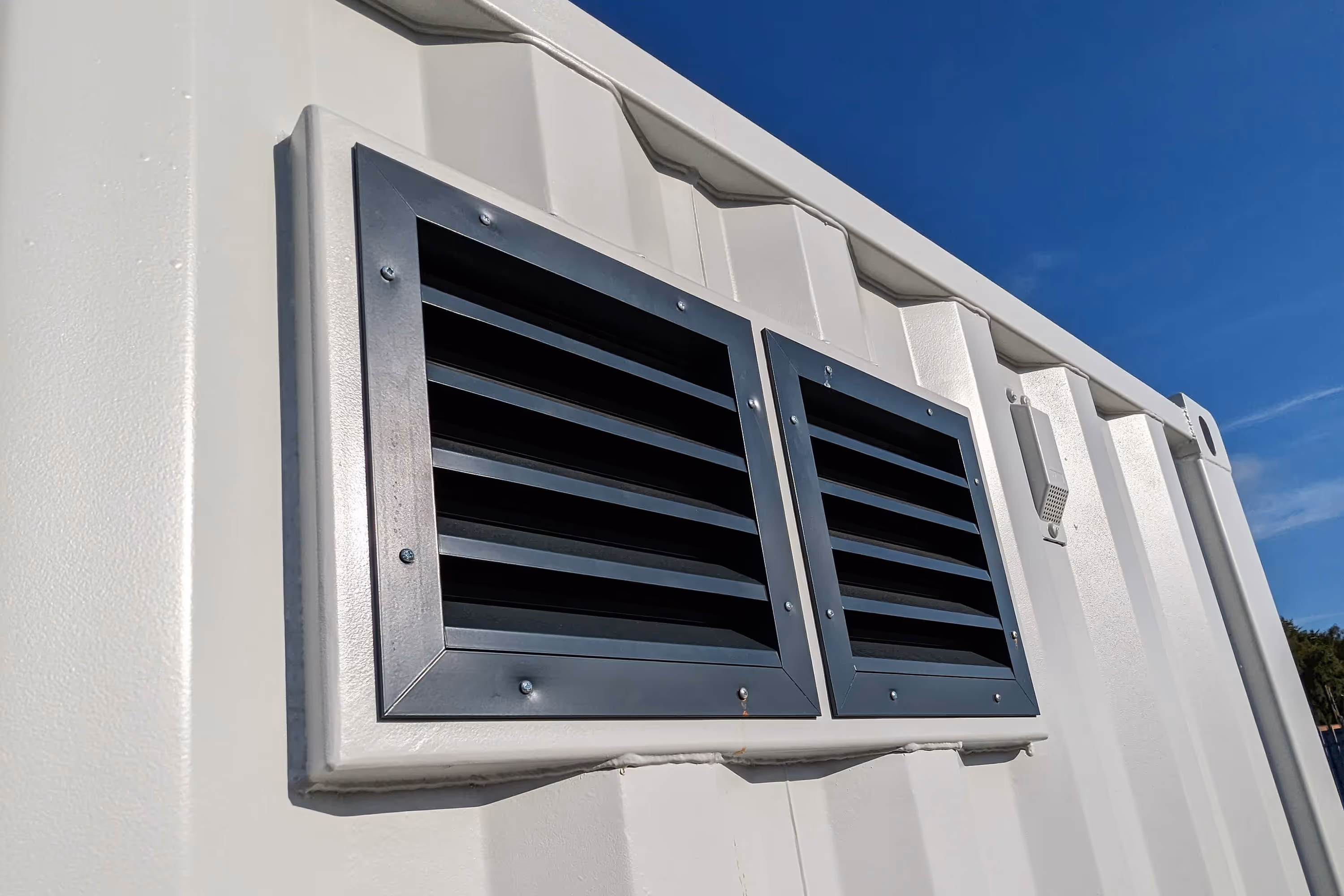 A white building with a vent on the side.