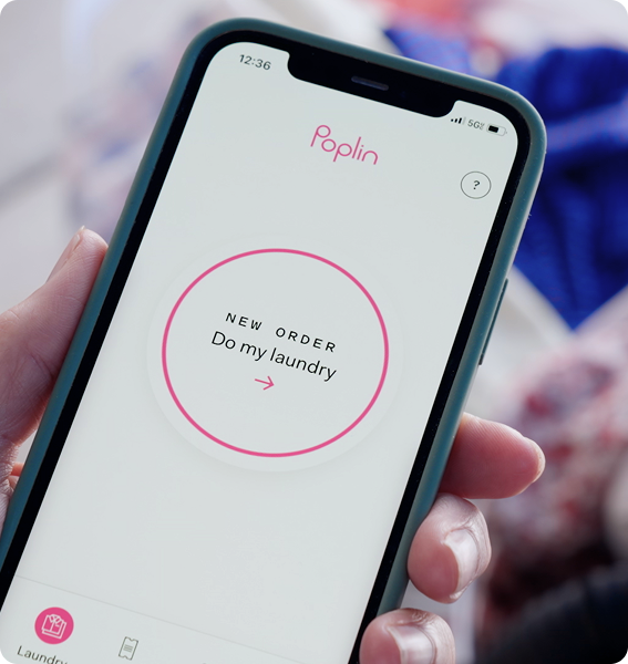 Hand holding phone showing Poplin app screen with a button labeled “New Order: Do my laundry.