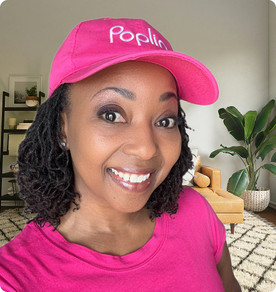 Smiling Poplin Laundry Pro wearing a pink Poplin hat and shirt, standing in a bright living room.