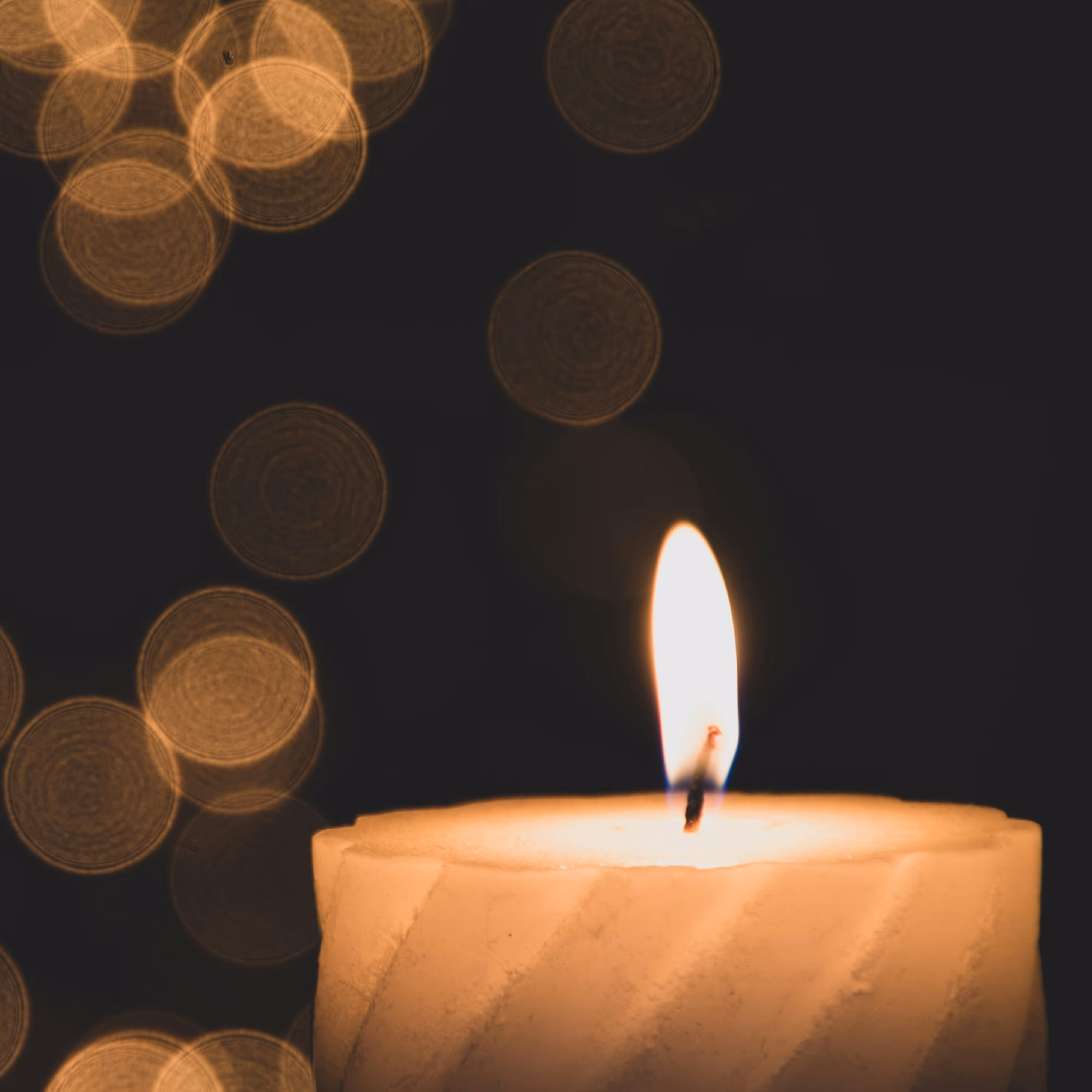 close up on a white, lit candle in a dark room 