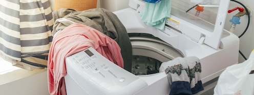 Tangled laundry spilling out of an open washing machine, capturing the chaos of a load that never seems to get finished