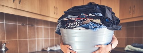 Person carrying an overflowing laundry basket, representing the hidden effort and time that goes into laundry beyond just running the machine